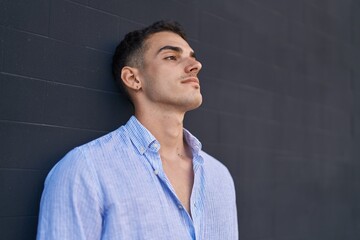 Young hispanic man with relaxed expression standing over black isolated background