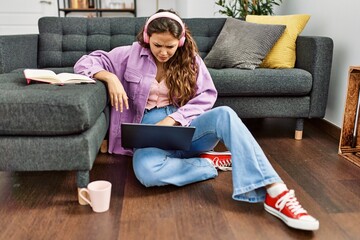 Young beautiful hispanic woman having video call sitting on floor at home