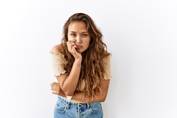 Beautiful hispanic woman standing over isolated while background looking stressed and nervous with...