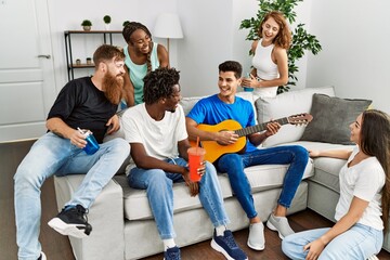 Group of young friends smiling happy and playing classical guitar at home.