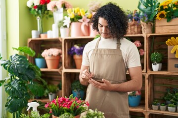 Young latin man florist writing on envelope letter at flower shop