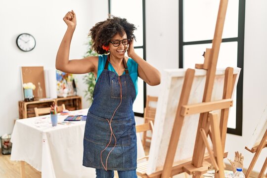 Young african american woman listening to music looking draw at art studio