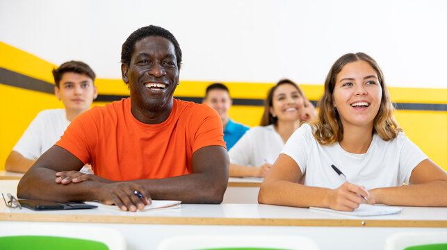 Cheerful smiling adult students at their desks in a university classroom