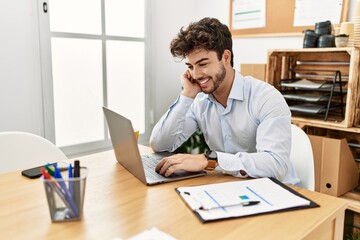 Young hispanic businessman smiling happy working at the office.