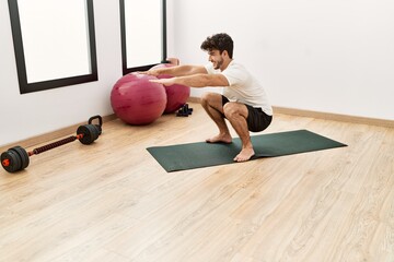 Young hispanic man smiling confident training legs exercise at sport center