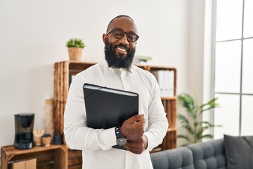 Young african american man psychologist holding binder at psychology center - obrazy, fototapety, plakaty