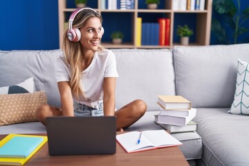 Young blonde woman student sitting on sofa studying at home