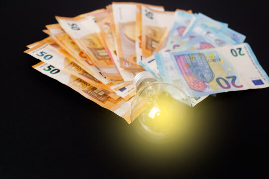 lighted light bulb with euro banknotes in the background