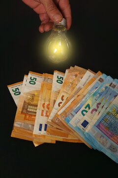 lighted light bulb with euro banknotes in the background