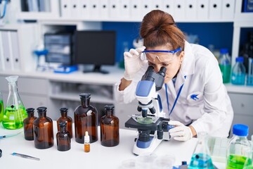 Young woman scientist using microscope working at laboratory