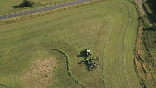Aerial Shot of Tractor and Rotary Rake Rowing Hay in a Field