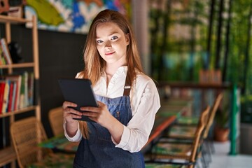 Young caucasian woman waitress smiling confident using touchpad at restaurant