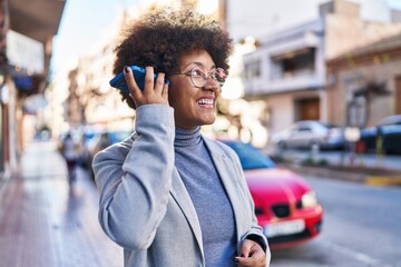 African american woman executive listening voice message by smartphone at street