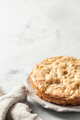 Traditional Charlotte with linen napkin on white marble background, apple pie. Text space