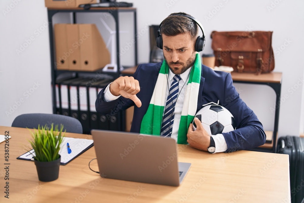 Canvas Prints Handsome hispanic man watching football game at the office with angry face, negative sign showing dislike with thumbs down, rejection concept