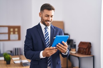 Young hispanic man business worker smiling confident using touchpad at office