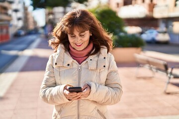 Middle age woman smiling confident using smartphone at park