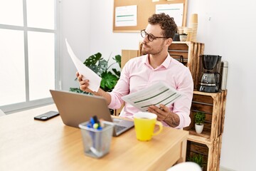 Fototapeta premium Young hispanic man reading document working at office