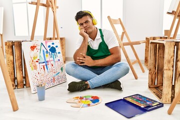 Young hispanic man at art studio thinking looking tired and bored with depression problems with crossed arms.