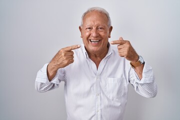 Senior man with grey hair standing over isolated background smiling cheerful showing and pointing with fingers teeth and mouth. dental health concept.