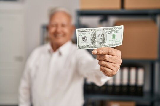Senior man ecommerce business worker holding dollar at office