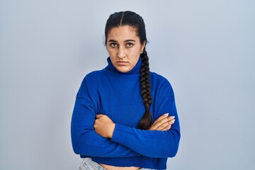 Young hispanic woman standing over isolated background skeptic and nervous, disapproving expression...