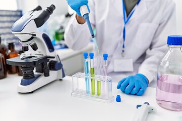 Fototapeta premium Young hispanic man wearing scientist uniform using pipette at laboratory