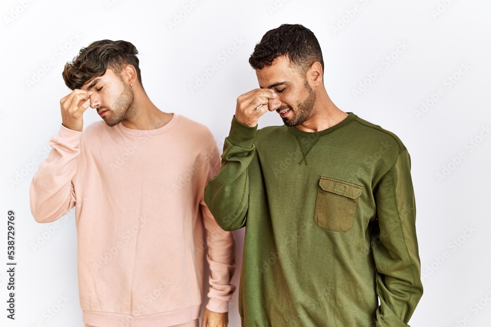 Poster young gay couple standing over isolated white background tired rubbing nose and eyes feeling fatigue