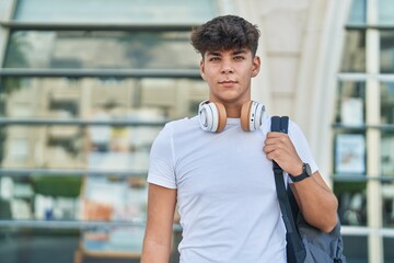 Young hispanic teenager student wearing backpack with relaxed expression at university