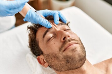 Obraz na płótnie Canvas Young hispanic man having facial anti-aging treatment at beauty center