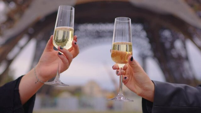 Beautiful happy girl couple celebrate wedding at an evening in front of the Eiffel Tower in Paris. Couple with glasses of champagne in a romantic place