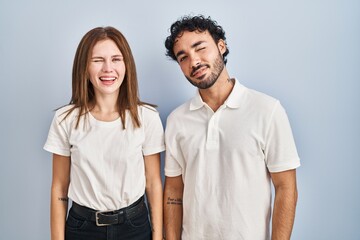 Young couple wearing casual clothes standing together winking looking at the camera with sexy expression, cheerful and happy face.