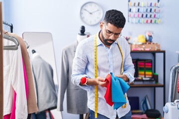 Young arab man tailor holding cloths at tailor shop