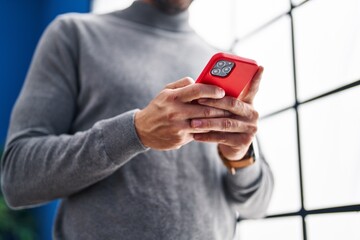 Young hispanic man using smartphone at home