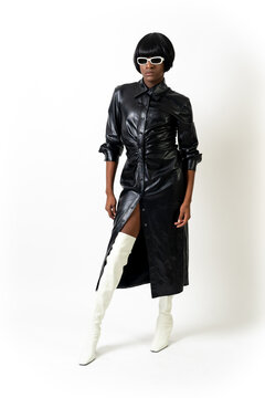 Black ethnic man in studio with white background, LGTBI concept, wearing leather skirt and sunglasses