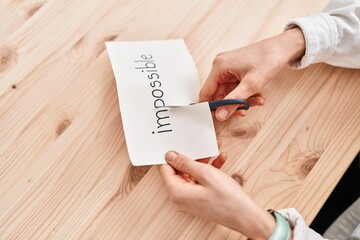 Young caucasian woman cutting impossible paper word at office
