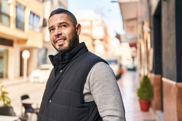 Obraz premium Young latin man smiling confident looking to the side at street