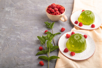 Mint and raspberry green jelly on gray concrete and orange linen textile. side view, copy space.
