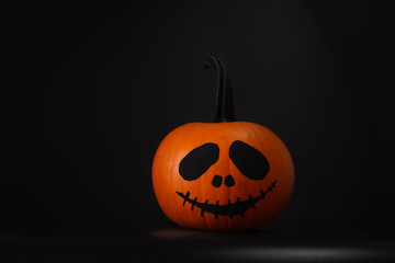 Halloween celebration. Pumpkin with drawn face on table in darkness, space for text
