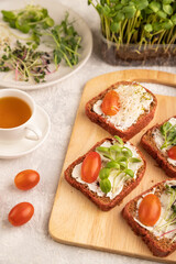Red beet bread sandwiches with cream cheese, tomatoes and microgreen on gray. side view, selective focus.