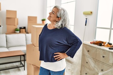 Middle age grey-haired woman smiling happy standing at new home.