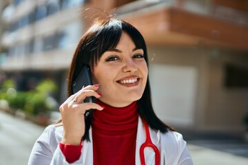 Young brunette woman wearing doctor uniform speaking on the phone at the city