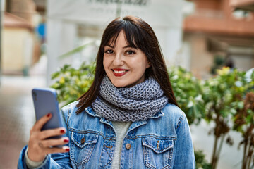 Young brunette woman smiling happy using smartphone at the city