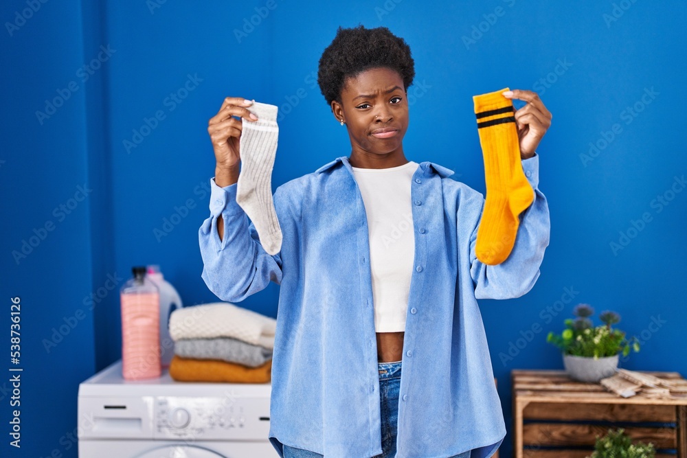 Poster African american woman holding clean andy dirty socks skeptic and nervous, frowning upset because of problem. negative person.