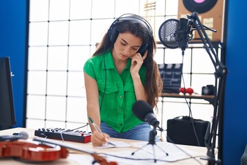 Young hispanic woman artist composing song at music studio