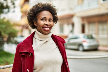 Beautiful business african american woman with afro hair smiling happy and confident outdoors at the city