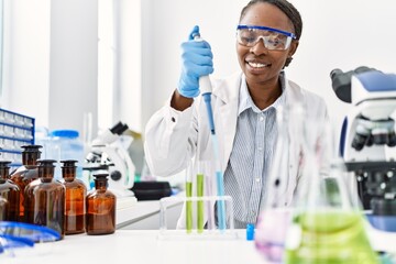 African american woman scientist pouring liquid on test tube at laboratory