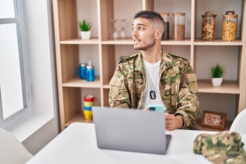 Young hispanic man army soldier using laptop and smartphone at home