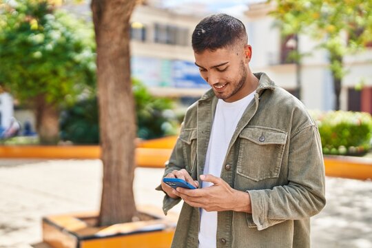Young hispanic man smiling confident using smartphone at park