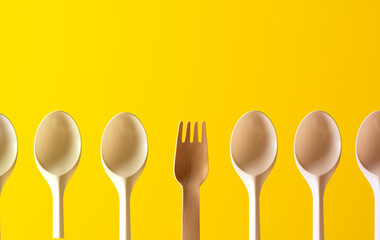 pattern of plastic spoons and wooden forks, yellow background
